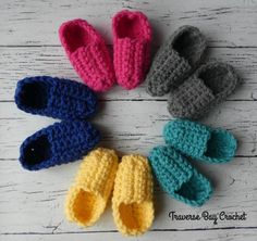 crocheted baby booties are arranged in a circle on a white wooden surface