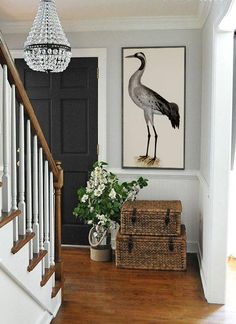 a bird is hanging on the wall next to a basket and vase with flowers in it