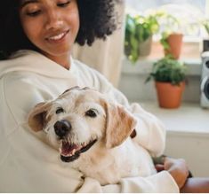 a woman holding a dog in her arms