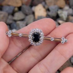 This antique circa 1900 brooch is centered with one (1) cushion cut natural sapphire set into a twelve-prong yellow gold setting. The sapphire is bordered with twelve (12) old European cut diamonds that are prong/ semi- bezel set into platinum topped 18K yellow gold settings. The brooch is also accented with eight (8) old European cut diamonds set into platinum bezel settings. The brooch measures 50.2mm X 14.6mm. Elegant Sapphire Diamond Brooches, Elegant Sapphire Diamond Brooch, Formal Sapphire Diamond Brooches, Formal Sapphire Diamond Brooch, Classic Diamond Brooch With Gemstones, Classic Diamond Gemstone Brooches, Elegant Sapphire Brooch Jewelry, Elegant Sapphire Brooch For Gift, Elegant Sapphire Brooches For Formal Occasions