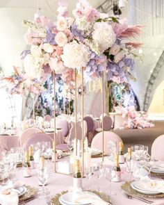 a tall vase filled with pink and white flowers on top of a dining room table