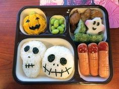 a bento box filled with rice, vegetables and fruit decorated to look like skeletons