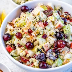 a white bowl filled with fruit salad next to two bowls full of grapes and other fruits