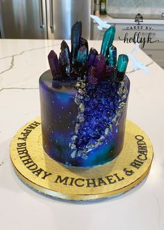 a cake that is on top of a table with blue and purple frosted icing