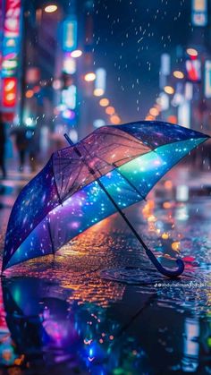 an open umbrella sitting on the side of a wet street in the rain at night