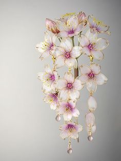 a bunch of flowers that are hanging from a hook on a wall in front of a gray background