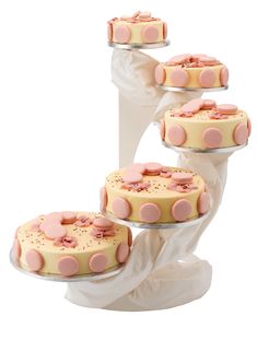 three tiered cake stand with pink and white cakes on it's trays