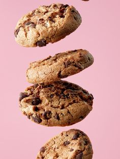 chocolate chip cookies falling into the air on a pink background with one cookie in the foreground