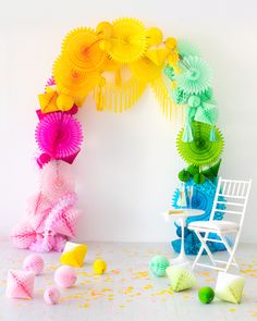 a white chair sitting in front of a wall with colorful paper decorations on top of it