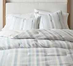 an unmade bed with blue and white striped sheets