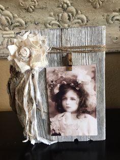 an old photo is attached to a wooden frame with a flower on it and some string