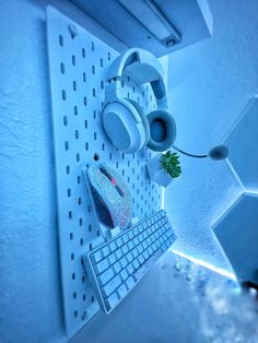 a computer keyboard sitting on top of a white shelf next to a mouse and plant