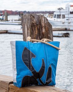 a blue and white bag sitting on top of a wooden post next to the water