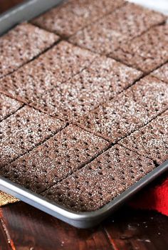 a pan with some brownies in it sitting on a table next to a red towel