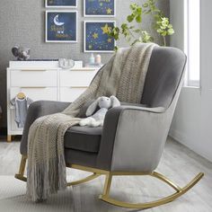 a rocking chair with a blanket and stuffed animal on it in front of a window