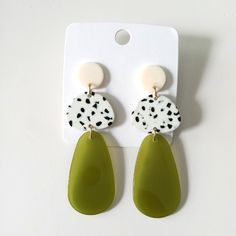 a pair of green and white earrings with polka dots on the top, hanging from a hook