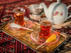 two cups of tea on a tray with spoons