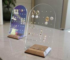 two clear acrylic displays with wooden base and earring hooks on top of each one