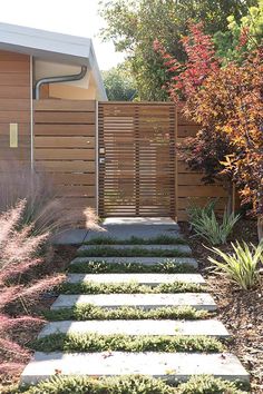 a garden with steps leading up to a fenced in area that is next to a house