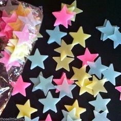 a bag filled with star shaped candies on top of a purple table next to pink and white stars