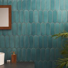 a bathroom with blue tiles and a mirror on the wall next to a potted plant