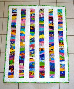 a close up of a colorful quilt on the floor with white tiles in the background