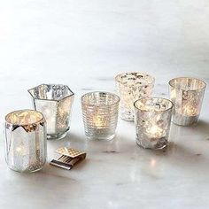 a group of glass candles sitting on top of a white table next to each other