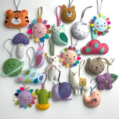 a bunch of small stuffed animals hanging from strings on a white surface with other items in the background