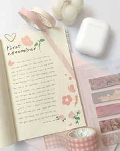 an open book with pink flowers on it next to some tape and other things that are laying around