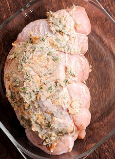 a close up of a chicken in a glass bowl on a wooden table with other food items