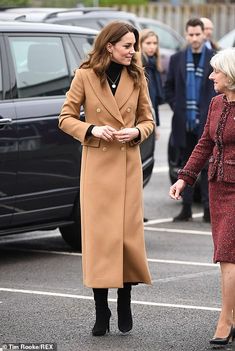 two women in coats are talking to each other while others look on from the parking lot