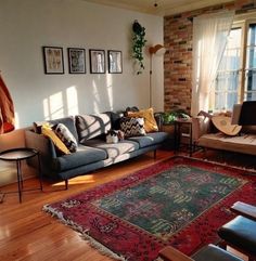 a living room filled with furniture next to a window and a rug on top of a hard wood floor