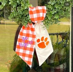 two orange and white gingham ties hanging from the side of a house window