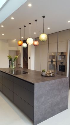 a large kitchen with an island and lights hanging from it's ceiling over the counter