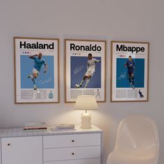 two soccer posters hang on the wall above a white dresser and side table with a lamp