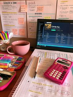 a pink calculator sitting on top of a desk next to a laptop computer