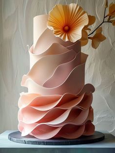 a three tiered cake decorated with pink and orange icing, topped with a large flower