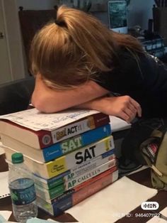 a woman leaning her head on a stack of books