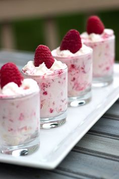 small desserts with raspberries and whipped cream in them on a white tray