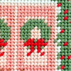 a close up view of a knitted piece of cloth with red flowers on it