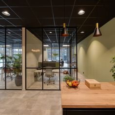 an office with glass walls and plants in the center