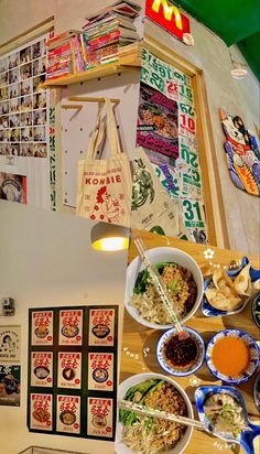 a table topped with bowls of food next to a wall covered in pictures and posters