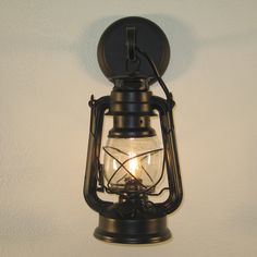 an old fashioned light hanging from the side of a wall with a candle in it