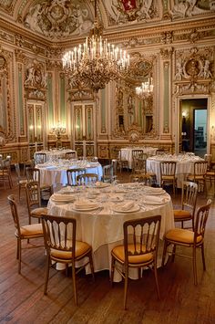 a fancy dining room with chandeliers and white table cloths on the tables