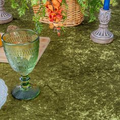 a table topped with glass vases filled with oranges and other items on top of a green surface