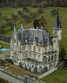 an aerial view of a large castle like building in the middle of a green field