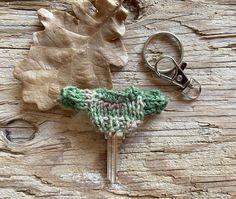 a green knitted object sitting on top of a wooden table next to a pair of scissors