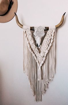 a cow skull hanging on the wall next to a hat