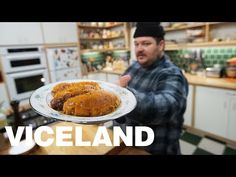 a man holding a plate with food on it in the middle of a kitchen area