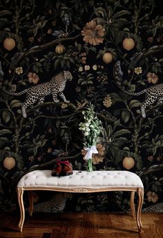 a leopard wallpapered with flowers and fruit on a bench in front of it